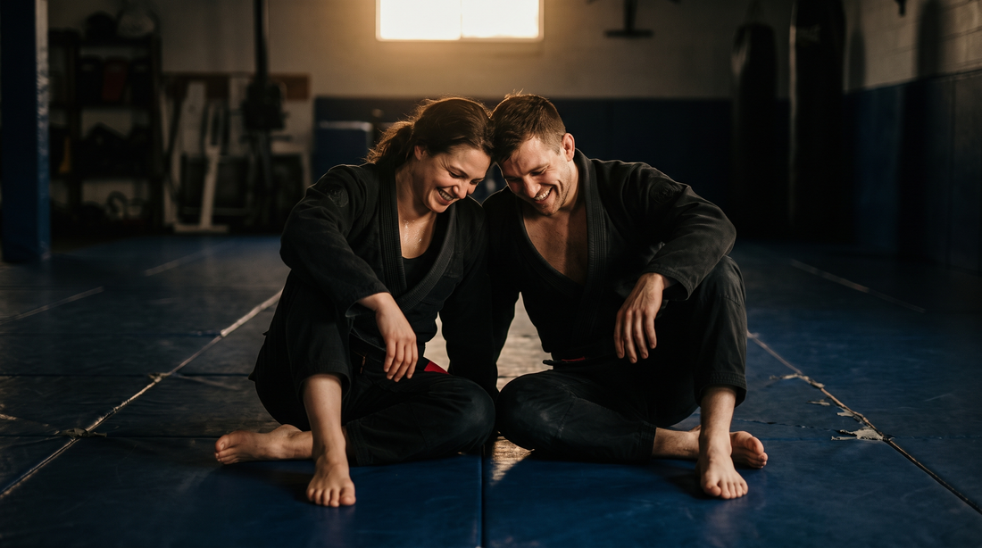 Couple in matching black gis laughing on the mats