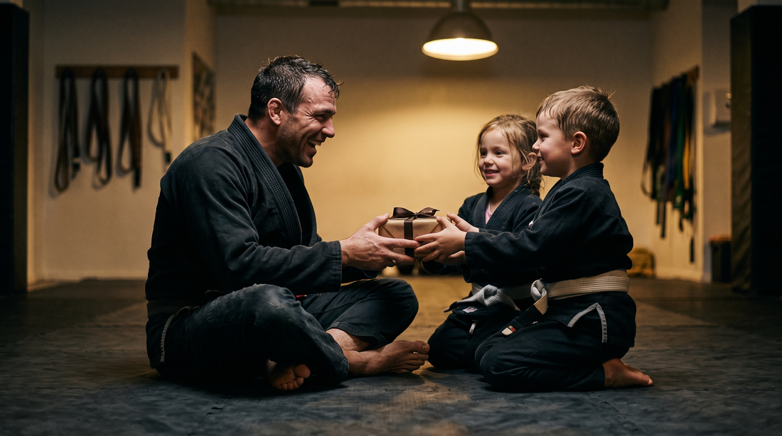 Dad in a black jiu-jitsu gi getting a gift from his kids on the mats