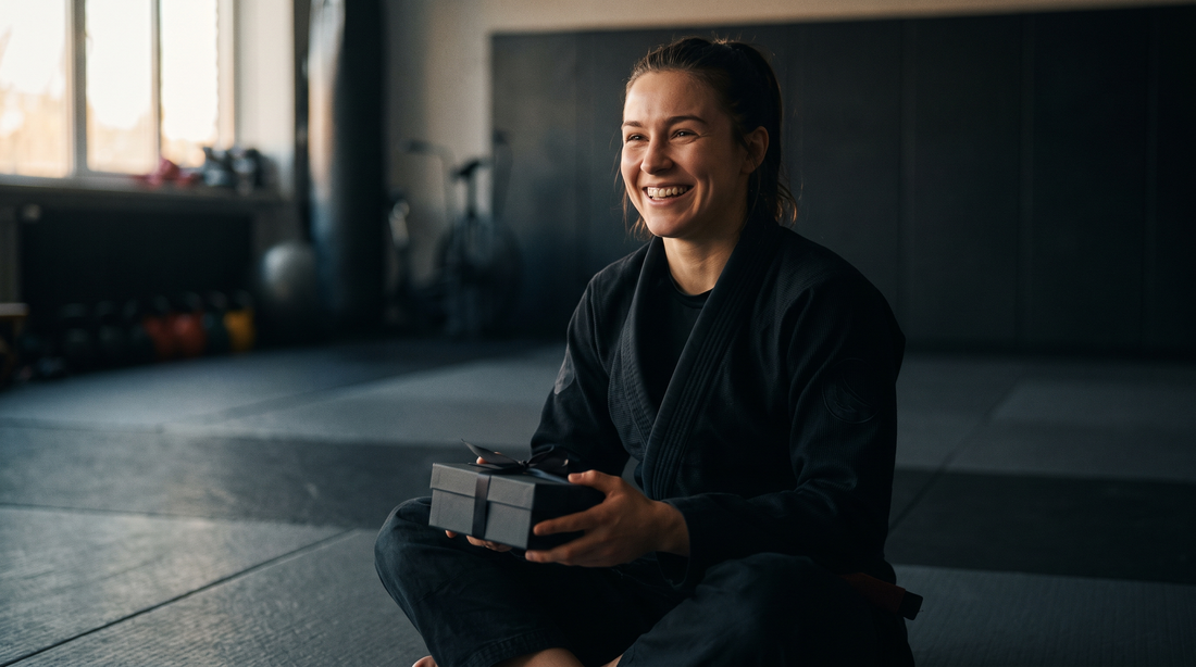 Woman in a black BJJ gi holding a gift box on the mats