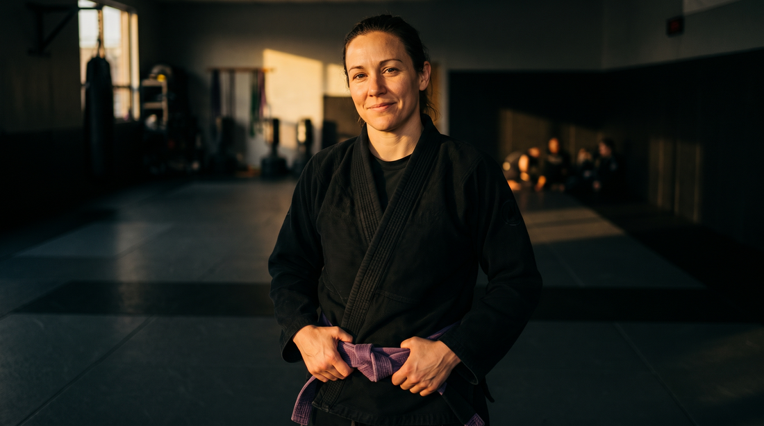Woman in a black gi tightening her purple belt